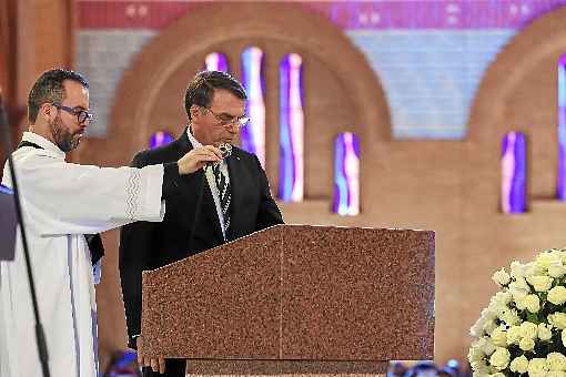 Bolsonaro faz a Primeira Leitura, uma parte da liturgia, durante missa na Basílica de Aparecida