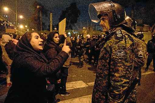 De dedo em riste, ativista confronta policial iraniano, durante protesto em memÃ³ria dos 176 mortos na tragÃ©dia aÃ©rea, em TeerÃ£