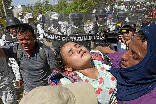 Mulher desmaia e Ã© amparada por um migrante, enquanto fogem da Guarda Nacional: gÃ¡s lacrimogÃªneo