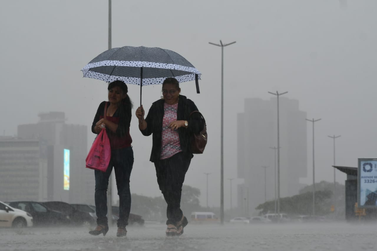 duas mulheres com guarda-chuva na chuva com o tempo bem cinza