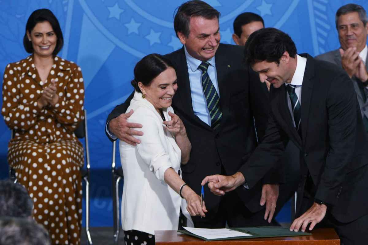 Regina Duarte assinando a posse ao lado de Bolsonaro e do ministro do Turismo Marcelo Alvaro Antonio