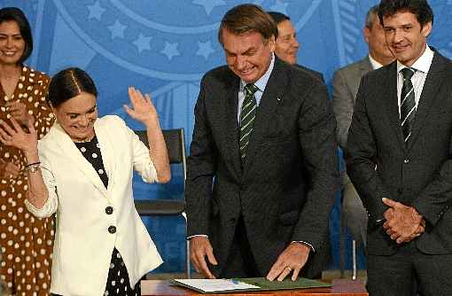 Regina Duarte e Bolsonaro olham o termo de posse durante cerimÃ´nia no Planalto: casamento polÃ­tico apÃ³s um namoro que comeÃ§ou em janeiro