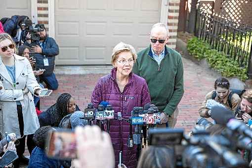 Observada pelo marido, Bruce Mann, Elizabeth Warren anuncia a decisÃ£o numa entrevista em frente  Ã  sua casa, em Cambridge, no estado de Massachusetts:  coleÃ§Ã£o de reveses