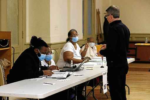 MesÃ¡rios usam mÃ¡scaras de proteÃ§Ã£o em um posto de votaÃ§Ã£o em Detroit: avanÃ§o do coronavÃ­rus fez com que comÃ­cios fossem cancelados