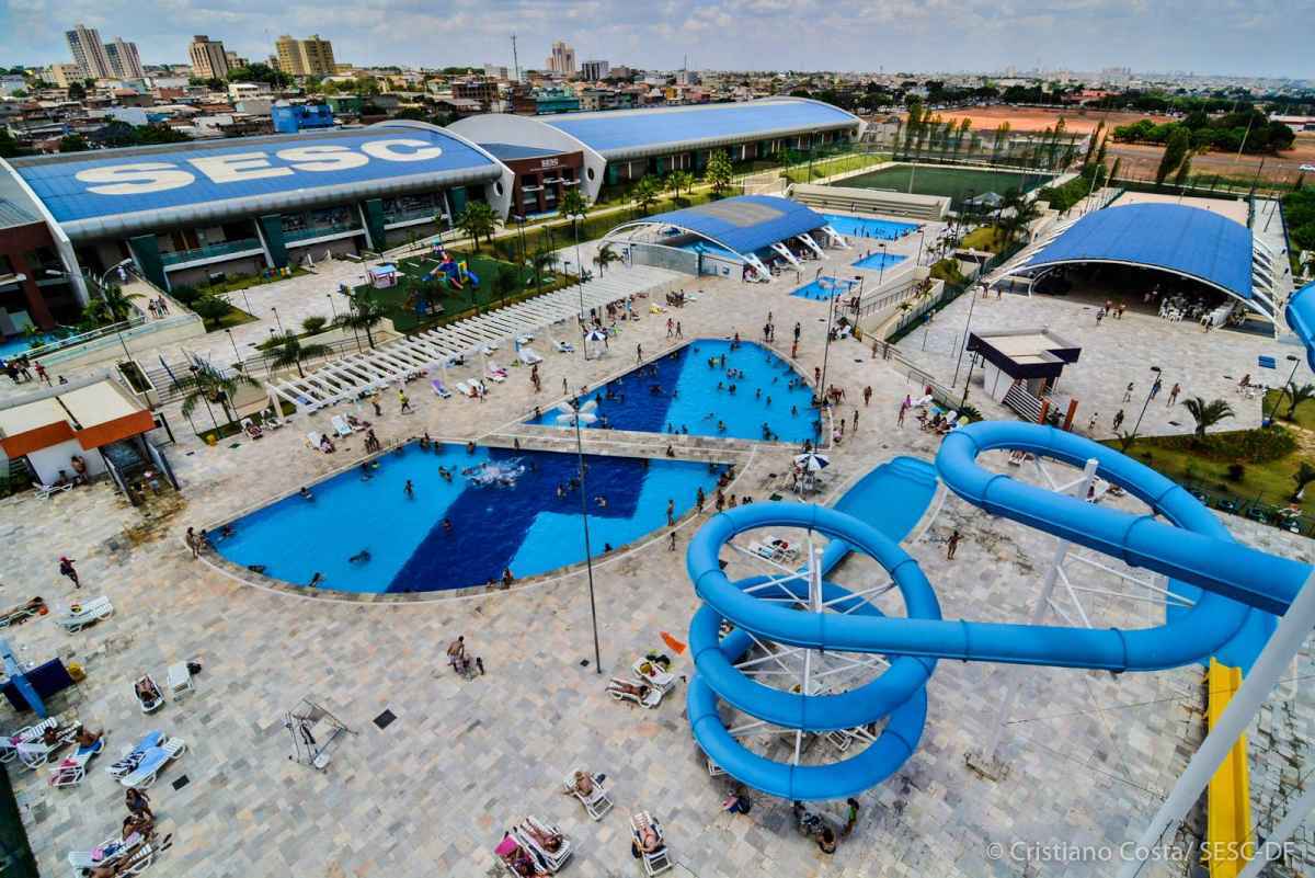 Unidade do Sesc-DF com piscinas e tobogÃ£s sendo utilizados por pessoas.