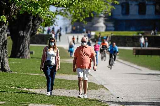 Casal  aproveita o dia ensolarado para dazer uma caminhda, em parque de Bruxelas, no domingo: paÃ­s formou comissÃ£o para avaliar volta Ã  rotina