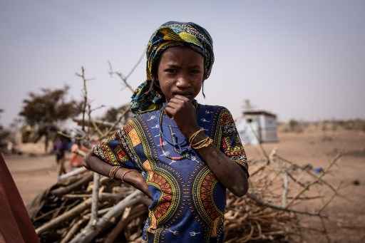 Menina encara a cÃ¢mera em campo de refugiados.