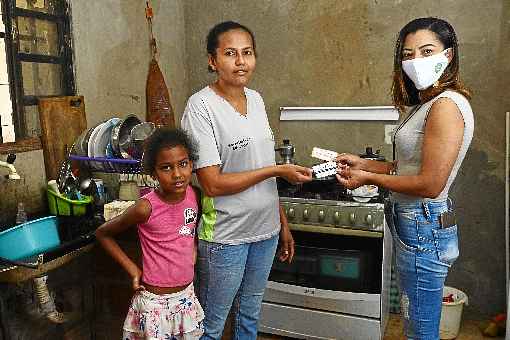 Francisca Oliveira e a filha Ana LuÃ­sa recebem cupom de alimentaÃ§Ã£o da auxiliar do projeto Francely Rocha