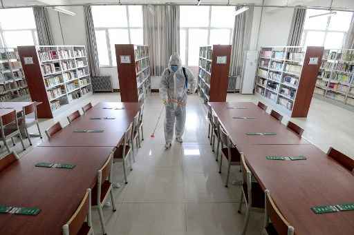 Um membro da equipe pulveriza desinfetante na biblioteca de uma escola enquanto se prepara para reabrir depois que o prazo de abertura foi adiado devido ao surto de coronavÃ­rus Covid-19.