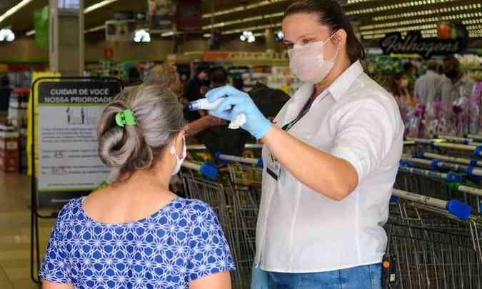 FuncionÃ¡ria mede temperatura de cliente na entrada de supermercado