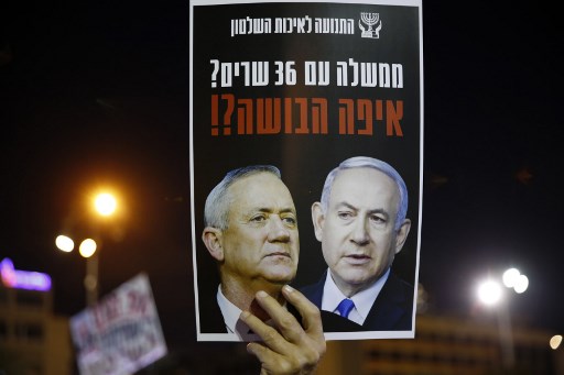 Um manifestante carrega um cartaz com uma foto do primeiro-ministro Benjamin Netanyahu (R) e seu rival que virou parceiro Benny Gantz, durante uma manifestaÃ§Ã£o na PraÃ§a Rabin de Tel Aviv.