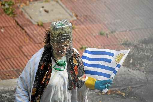 MÃ¡scara improvisada com garrafa de Ã¡gua mineral, luvas de borracha e a bandeira nacional nas mÃ£os: flagrante em MontevidÃ©u, no mÃªs passado