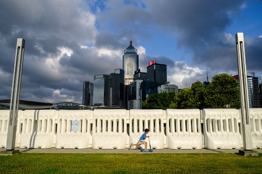 Menino anda de patinete em frente a prÃ©dios em Hong Kong, China.