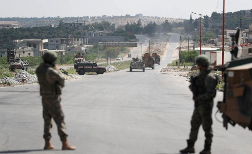 Soldados turcos vigiam enquanto veÃ­culos militares de uma patrulha conjunta russo-turca passam pela estrada M4 nos arredores da cidade de Ariha, controlada pelos rebeldes, na provÃ­ncia de Idlib, no noroeste da SÃ­ria, em 7 de maio de 2020.