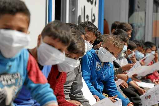 Meninos sÃ­rios, com mÃ¡scaras, recebem orientaÃ§Ãµes de prevenÃ§Ã£o em centro de refugiados na Turquia: diagnÃ³stico Ã© mais difÃ­cil nos pequenos