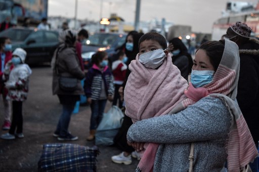 Nesta foto de arquivo tirada em 4 de maio de 2020, uma mulher segura seu filho quando migrantes transferidos do campo de Moria, na ilha de Lesbos, desembarcam no porto de Pireu, perto de Atenas.