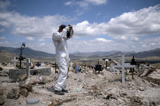 Um coveiro se prepara para dois enterros do covid-19 no CemitÃ©rio Municipal # 13 em Tijuana, estado de Baja California, MÃ©xico, em 12 de maio de 2020, durante a pandemia de coronavÃ­rus.