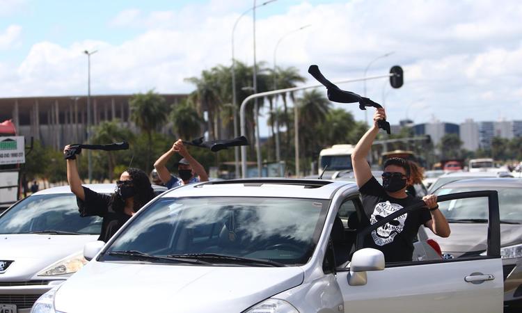 De dentro dos carros, os manifestantes balanÃ§am um tecido preto e flores, em sinal de luta pela morte do colega