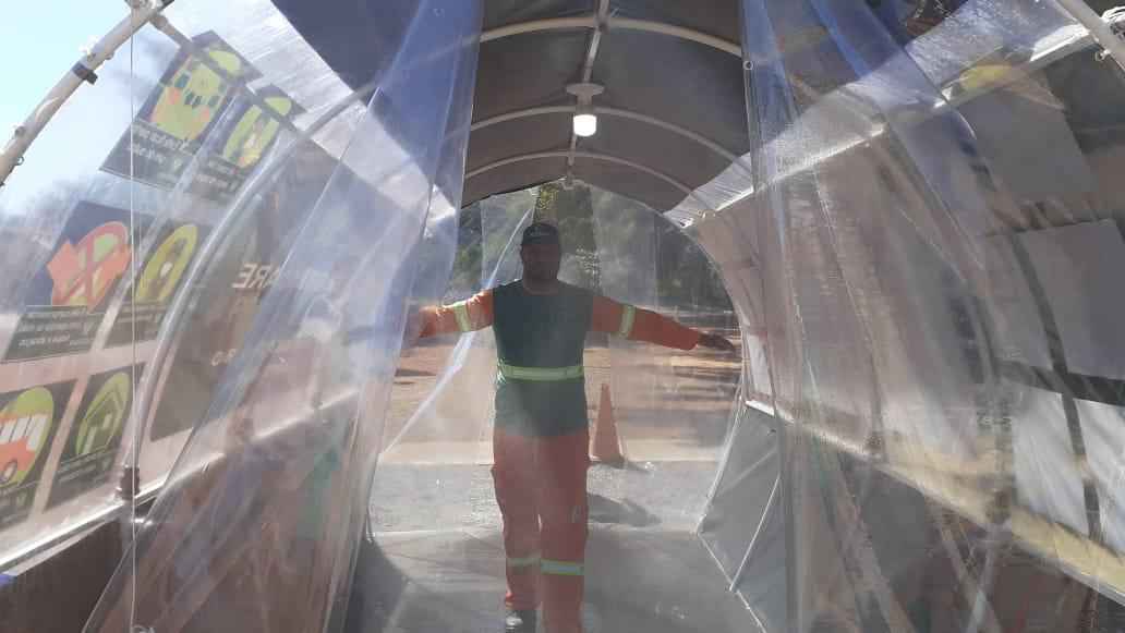 Antes e depois do expediente, trabalhadores atravessam o equipamento, que asperge produto com aÃ§Ãµes anti bactericida, fungicida e viral