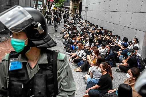 Policial vigia ativistas prÃ³-democracia detidos no distrito de Causeway Bay: repressÃ£o com spray de pimenta