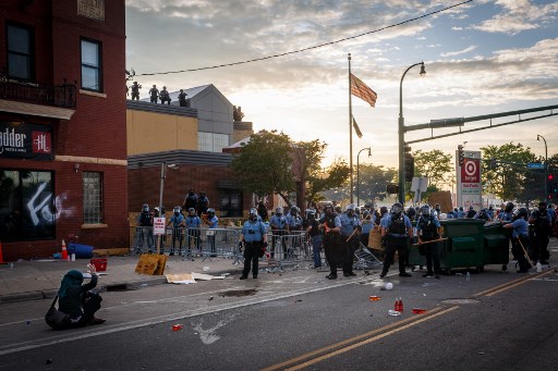 Nesta foto tirada em 27 de maio de 2020, um manifestante se senta no chÃ£o e gesticula para os policiais de Minneapolis durante uma manifestaÃ§Ã£o sobre a morte de George Floyd do lado de fora da Terceira Delegacia de PolÃ­cia em Minneapolis, Minnesota.