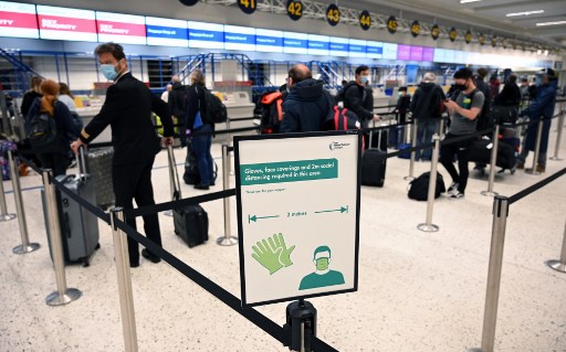 Os passageiros que usam EPI (equipamento de proteÃ§Ã£o individual), incluindo uma mÃ¡scara facial como medida de precauÃ§Ã£o contra o COVID-19, se distanciam socialmente enquanto fazem fila em um balcÃ£o de check-in no aeroporto de Manchester, no norte da Inglaterra.