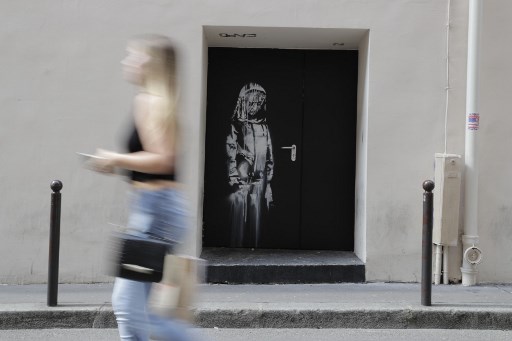 Foto de arquivo tirada em 25 de junho de 2018, uma mulher passa por uma obra de arte do artista de rua Banksy em Paris.