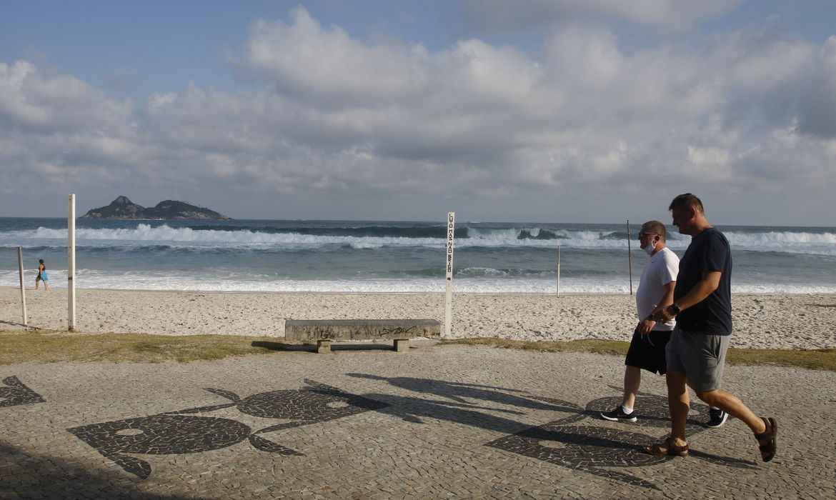 Duas pessoas caminhando na orla da praia.