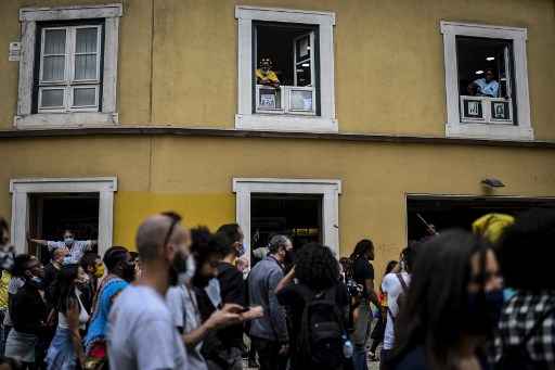 Pessoas observam manifestantes de suas janelas durante uma manifestaÃ§Ã£o contra o racismo e o fascismo em Lisboa em 6 de junho de 2020.