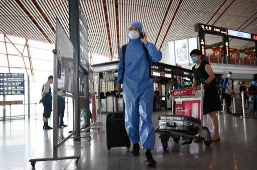 Um homem vestindo um traje de proteÃ§Ã£o usa seu telefone no aeroporto internacional de Pequim em 17 de junho de 2020.