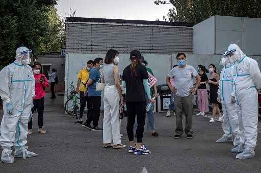 Trabalhadores usando equipamento de proteÃ§Ã£o individual (EPI) cuidam de um grupo de pessoas usando mÃ¡scaras enquanto esperam para se submeter aos testes de coronavÃ­rus covid-19, em Pequim, em 19 de junho de 2020.