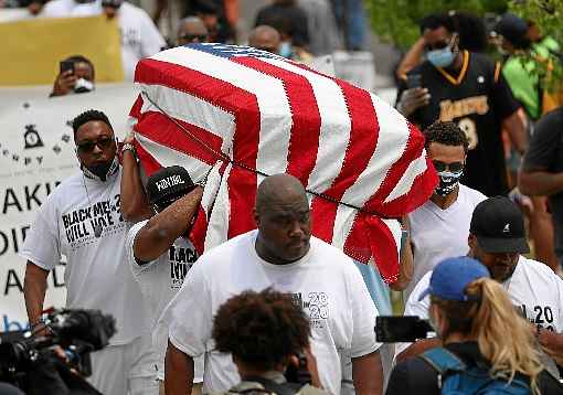 Ativistas do movimento Black Lives Matter carregam caixÃ£o vazio, em Tulsa, na vÃ©spera do comÃ­cio de Trump