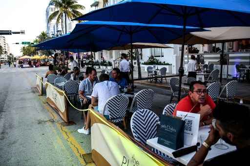 As pessoas comem na Ã¡rea de jantar ao ar livre de um restaurante na Ocean Drive em Miami Beach, FlÃ³rida.