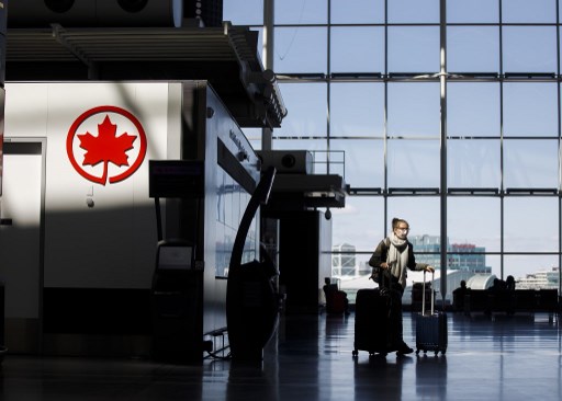 Nesta foto de arquivo, uma passageira carrega sua bagagem perto de um logotipo da Air Canada no Aeroporto Internacional Toronto Pearson em 1 de abril de 2020 em Toronto, CanadÃ¡.