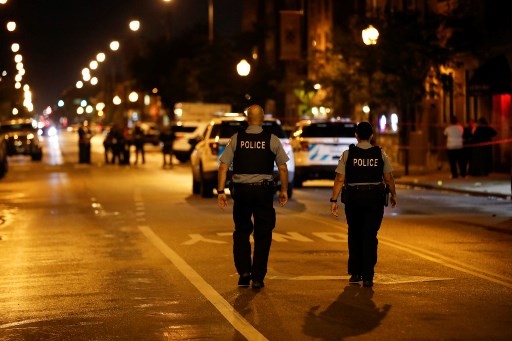 Pessoas ficam na frente do Rhodes Funeral Services (D) enquanto policiais de Chicago investigam a cena de um tiroteio em Chicago, Illinois.