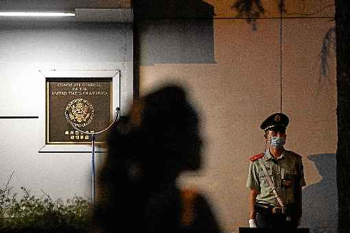 Policial mantÃ©m guarda na entrada do consulado dos Estados Unidos, em Chengdu, enquanto pedestre Ã© vista diante da representaÃ§Ã£o: novo 
foco de conflito