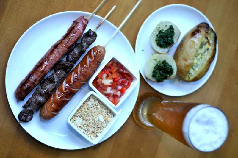 Espetinho de angus black, linguiÃ§a suÃ­na, salsichÃ£o acompanhados por vinagrete, farofa, pÃ£o de alho e caneca de chope, do Chicago Prime.