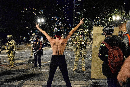 Mulher faz topless em protesto contra a presenÃ§a de soldados fortemente armados, nas imediaÃ§Ãµes do prÃ©dio da Corte Federal, em Portland