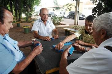 Cleomenes, 68 anos (ao centro), joga dominó com amigos na praça em frente de casa: 